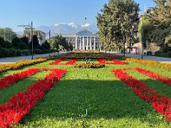 05C Flowers frame the view down Kyrgyz National State University to Bishkek City Hall with mountains beyond Bishkek Kyrgyzstan